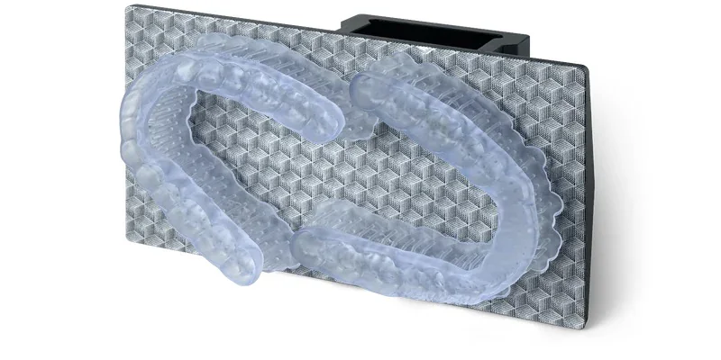 Phrozen Lumii DLP showing two clear dental aligners on a textured build plate, showcasing precision 3D printing capabilities.