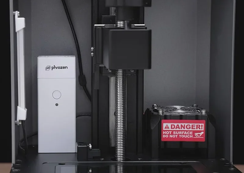 Phrozen Lumii DLP 3D printer interior with screw mechanism, branded component, and warning label.