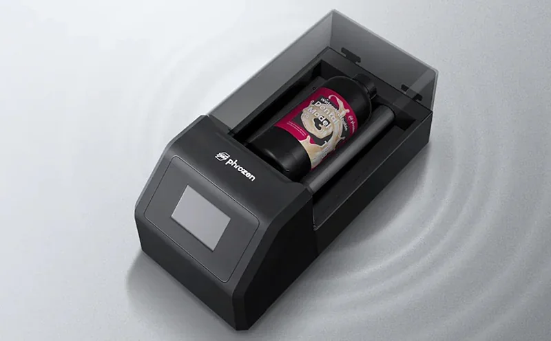 Phrozen Lumii DLP printer with touch screen panel, housing a bottle of resin. Gray casing featuring Phrozen branding, set against a light background.