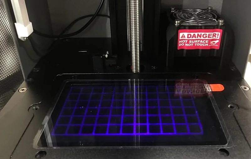 Phrozen Lumii DLP 3D printer interior showing grid-patterned print bed, cooling fan, and “Danger” warning sign on hot surface.