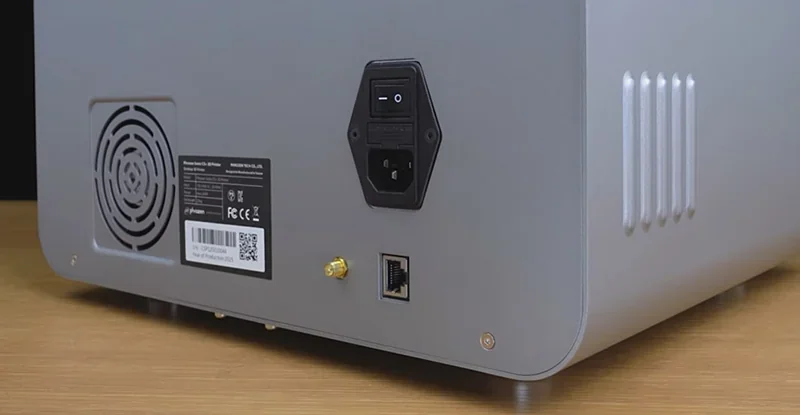 Phrozen Sonic CS+ 3D printer rear panel showing power switch, fan vent, and connectivity ports on a wooden surface.