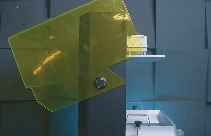 Phrozen Sonic Mega 8K with yellow protective cover, showing build platform and technical details, set against a padded wall.