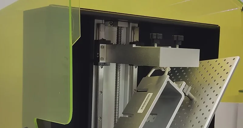 Phrozen Sonic Mega 8K 3D printer's open chamber showing metallic build plate and internal components with green-tinted acrylic cover.