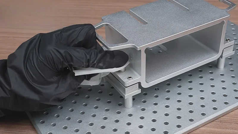 Gloved hand assembling a metal 3D-printed component on a perforated base, created using the Phrozen Sonic Mega 8K printer.