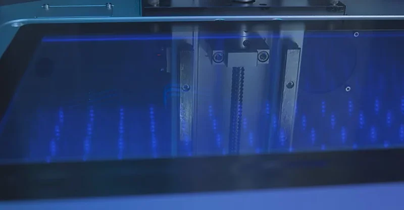 Phrozen Sonic Mega 8K 3D printer with illuminated build area displaying blue LED lights.