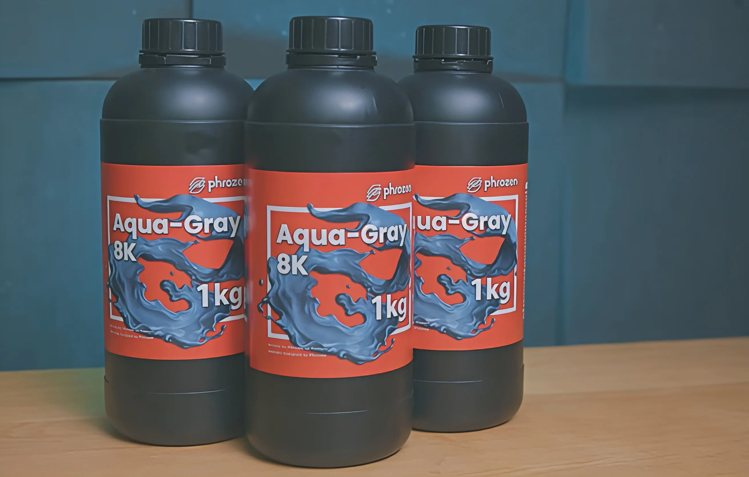 Phrozen Sonic Mega 8K resin bottles labeled Aqua-Gray 8K, 1kg each, with blue swirl design against a red background on a wooden table.