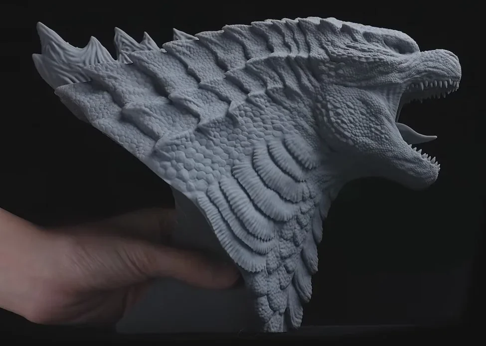 Dragon sculpture with intricate scales and open mouth, 3D printed by Phrozen Sonic Mega 8K, held in hand against a dark background.