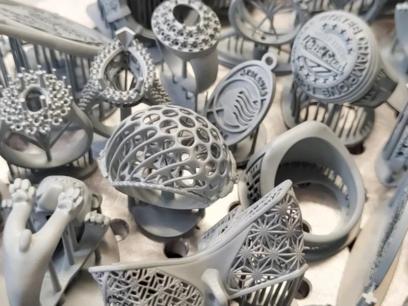 3D printed intricate gray models, including rings and abstract shapes, created by Phrozen Sonic Mega 8K V2, showcasing precision and detail.