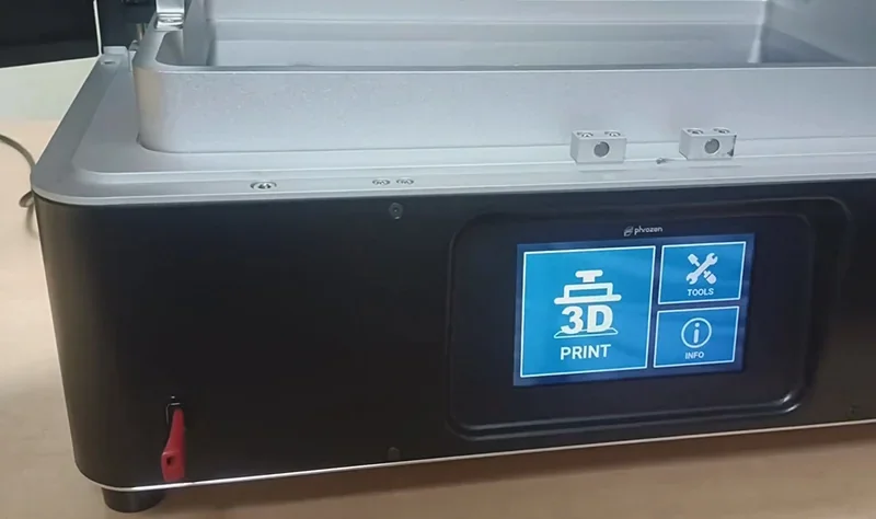 Phrozen Sonic Mega 8K V2 3D printer with touchscreen interface on a wooden table, displaying options for printing, tools, and info.