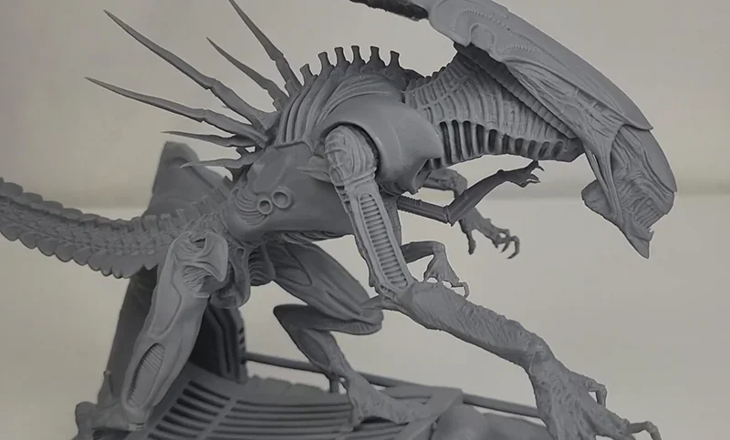 Intricate gray alien creature model 3D printed by Phrozen Sonic Mega 8K V2, showcasing detailed spikes, limbs, and textures on a plain backdrop.