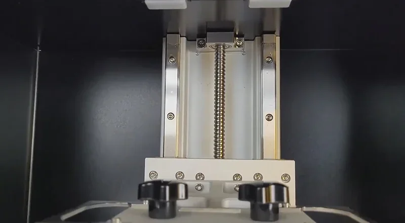 Phrozen Sonic Mega 8K V2 interior featuring a metal threaded rod mechanism centered within its sleek, dark enclosure, showcasing precision engineering.