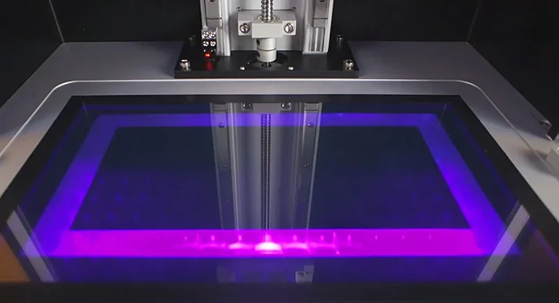 Phrozen Sonic Mega 8K v2 printing bed with purple UV light, showcasing precision and technology in resin 3D printing.