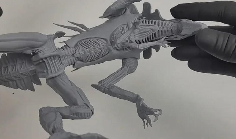 Detailed alien model printed by Phrozen Sonic Mega 8K V2, showcasing intricate design and smooth finish, held by gloved hands.