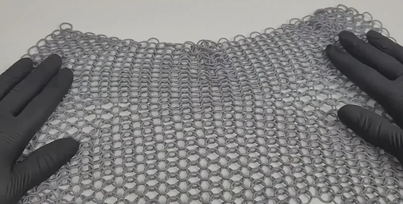 Chainmail sheet 3D printed by Phrozen Sonic Mega 8K V2, displayed between gloved hands, showcasing intricate link details on a neutral background.