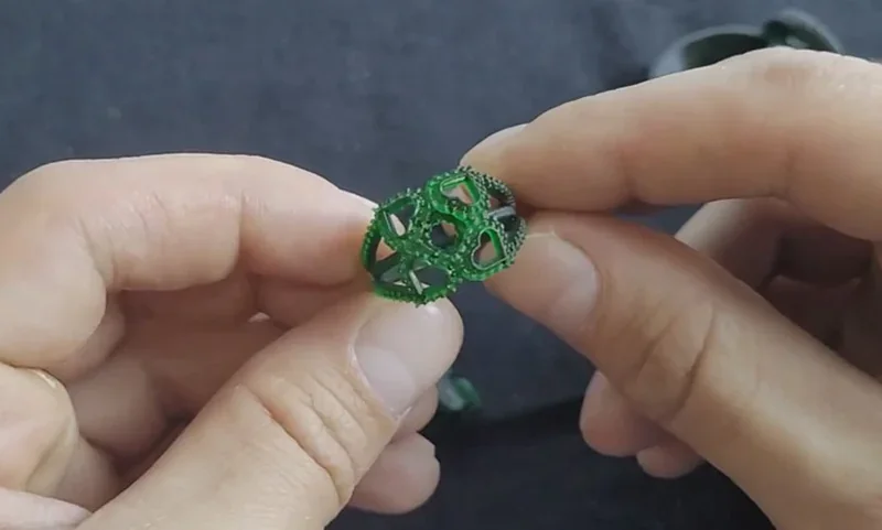 Hands holding a complex green 3D-printed geometric structure made by Phrozen Sonic XL 4K Plus, showcasing precise detail and craftsmanship.