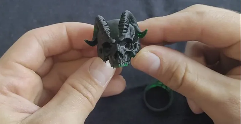 Hands hold a detailed gray and green skull model with horns, created by the Phrozen Sonic XL 4K Plus 3D printer.