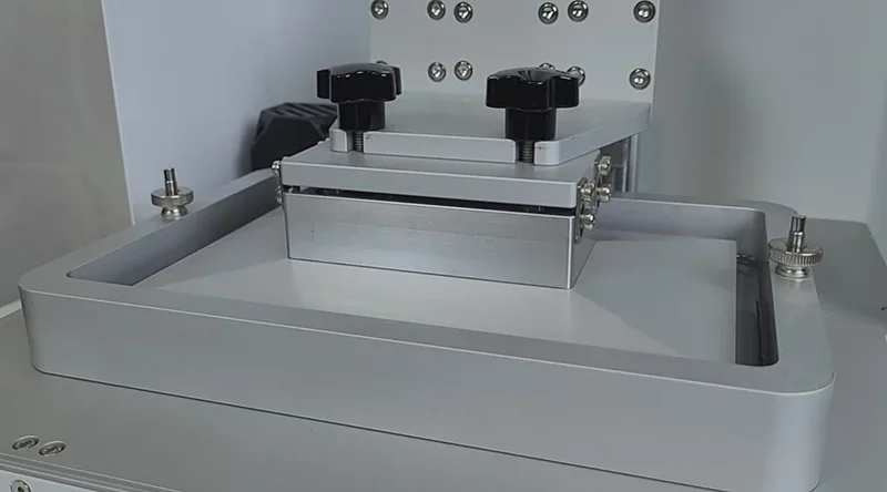 Phrozen Sonic XL 4K Plus 3D printer with metallic build platform and screws, set in a sleek, industrial design.