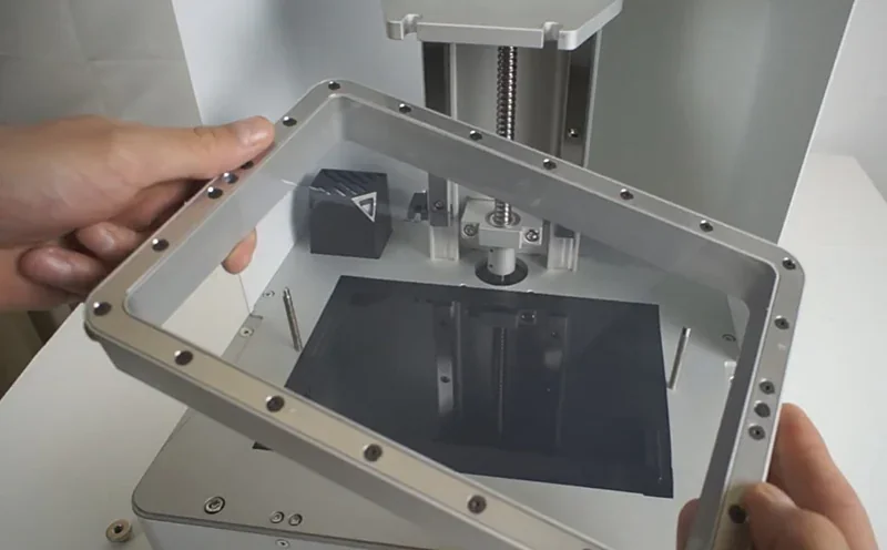 Phrozen Sonic XL 4K Plus printer with resin vat held above, showing detailed mechanical components and branding.