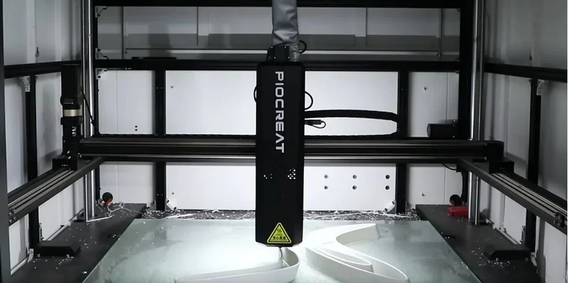 Piocreat G12 3D printer operating, creating white parts inside a high-tech enclosure, showcasing precision and modern design.
