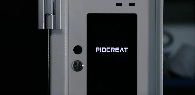 Piocreat G12 3D printer front panel with logo, featuring sleek design and control interface in a dimly lit setting.