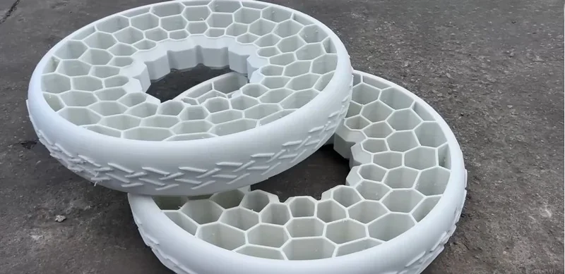 Two hexagonal-patterned white tires printed by the piocreat g12 rest on a concrete surface.