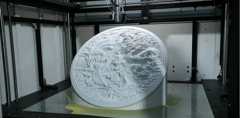 Piocreat G12 3D printer creating an intricate circular design with dragon motifs inside a large industrial setting.