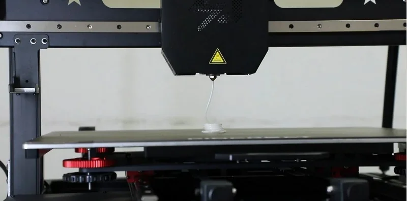 Piocreat G5 3D printer extruding material onto a build plate, showcasing precision technology in a professional, sleek black design.