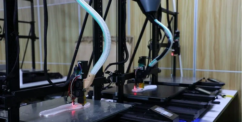 Piocreat G5 3D printers in operation, printing complex models on a workshop table with visible tubing and components.