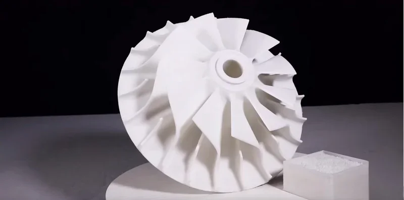 Piocreat G5-printed white turbine part with intricate blades and a square sample piece on a neutral background.