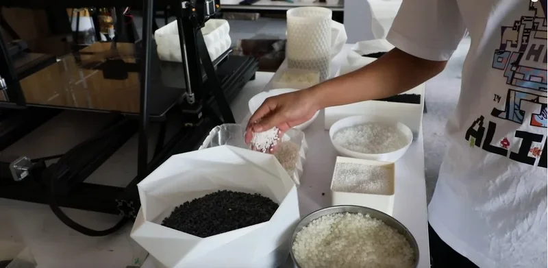 Piocreat G5 with various 3D-printed samples in a workshop setting, showcasing black and white material samples used by the printer.