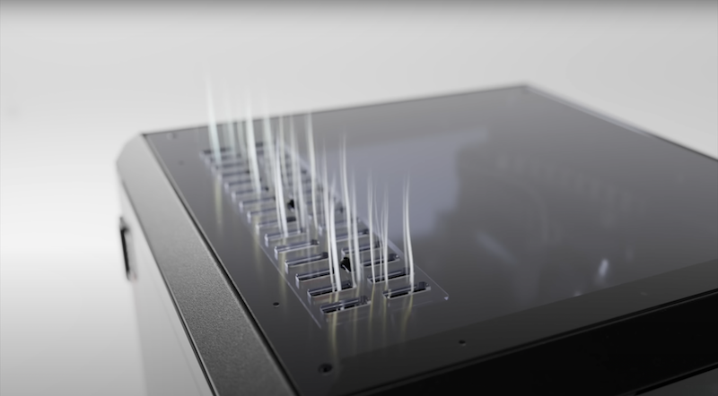 A close-up view of the Prusa Core One printer’s top featuring a series of small, sharp spikes protruding vertically from an array of slots. This detail appears to be part of a unique technical feature or design element of the printer. The structure is set against a sleek, matte black finish, highlighting the precision and cleanliness of the design in a studio setting with soft lighting.