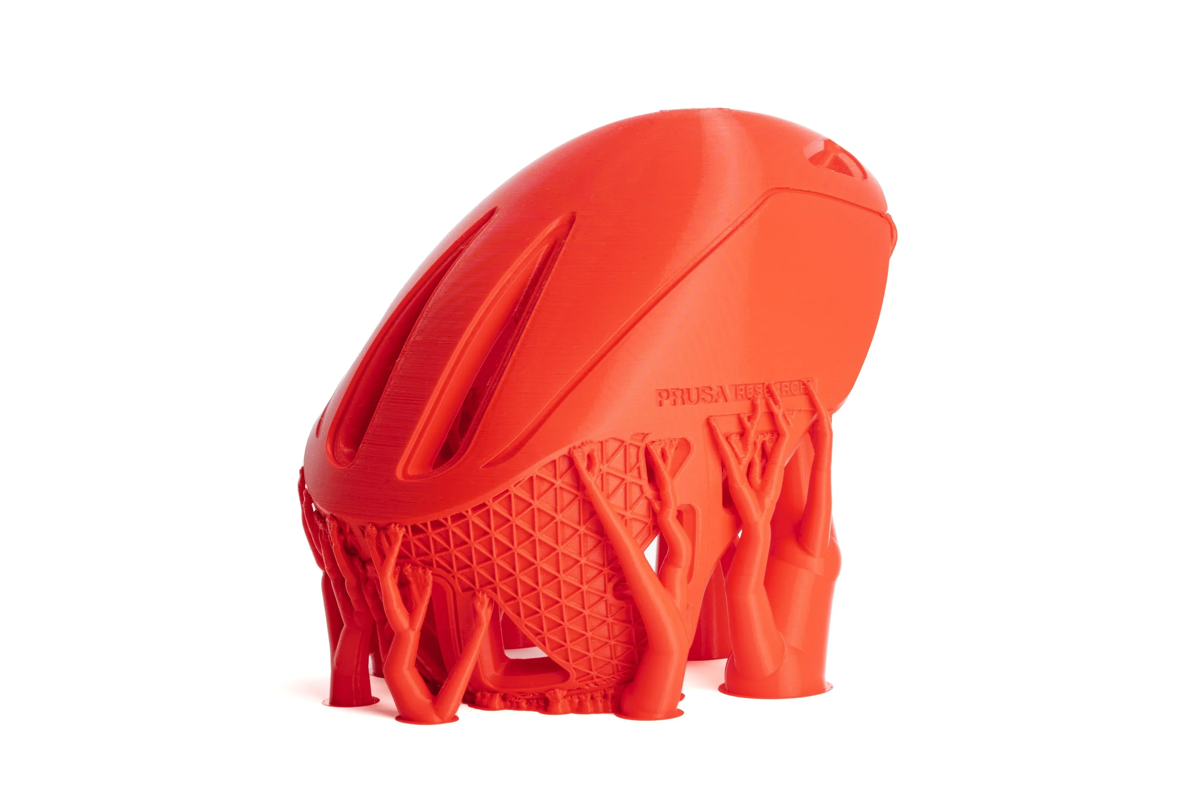 Red, elongated 3D-printed object with tree-like supports created by Prusa Core One. The main structure features sleek, aerodynamic grooves and branding.