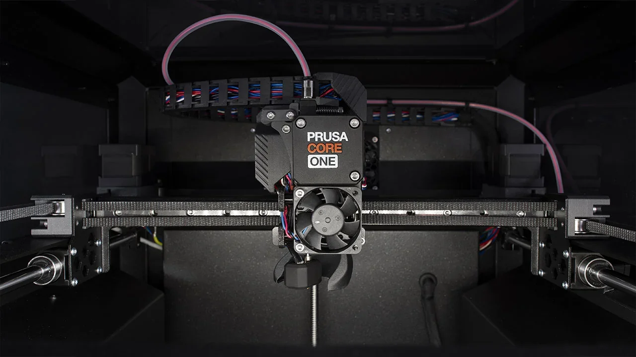 Prusa Core One 3D printer showcasing its interior with visible extruder and wiring, highlighting precise components and advanced technology.
