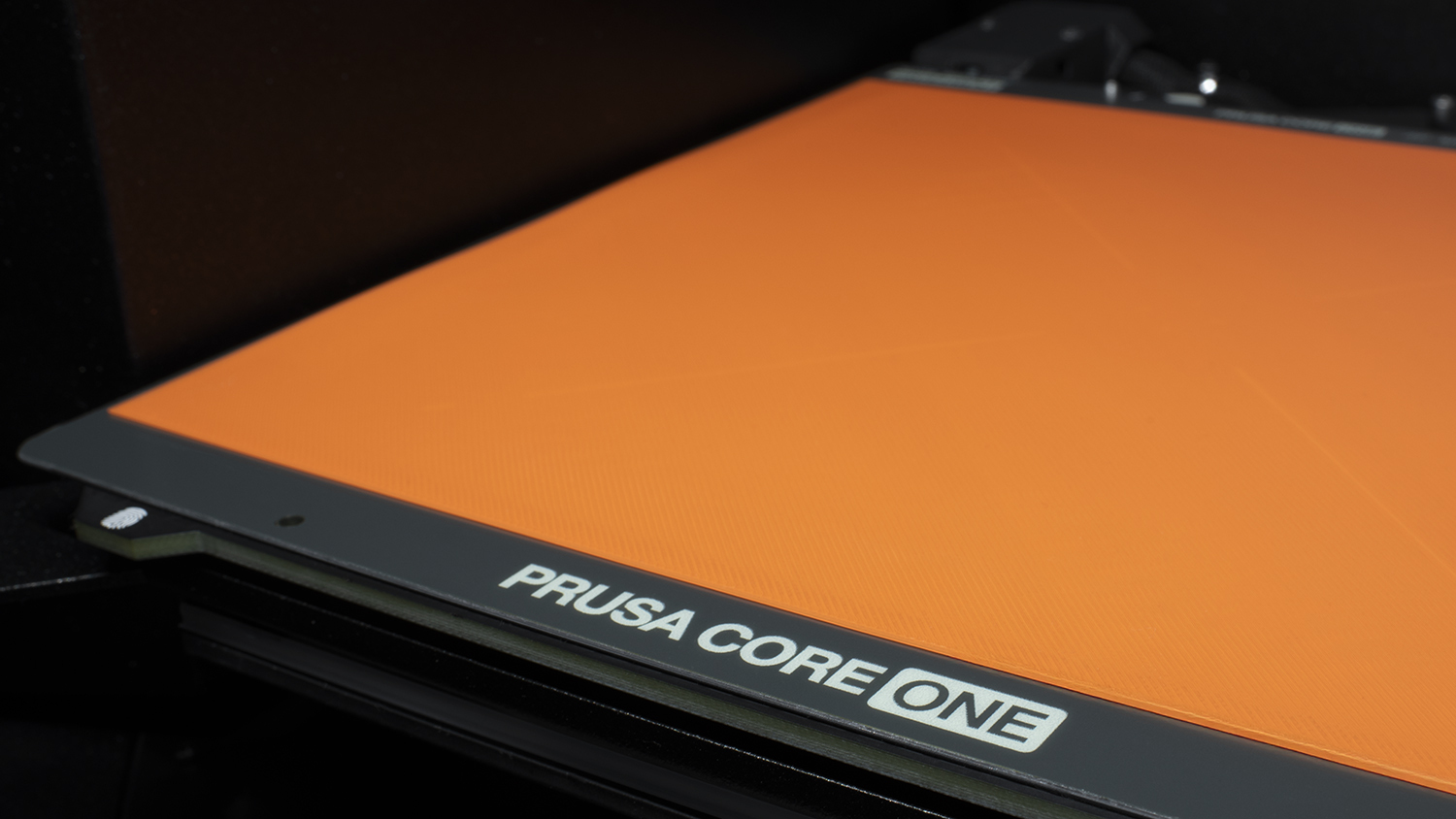 An orange 3D printer build plate with the label