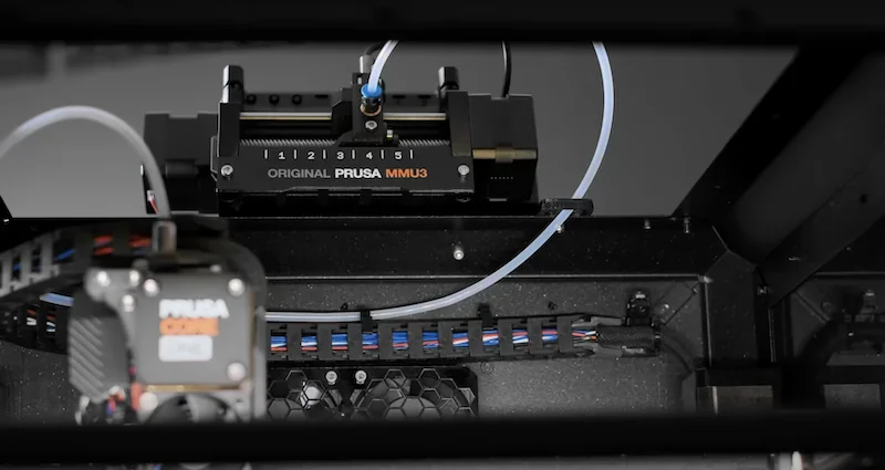 Prusa Core One 3D printer, showing detailed internal components, wires, and branding, highlighting precision engineering and Prusa MMU3 attachment.