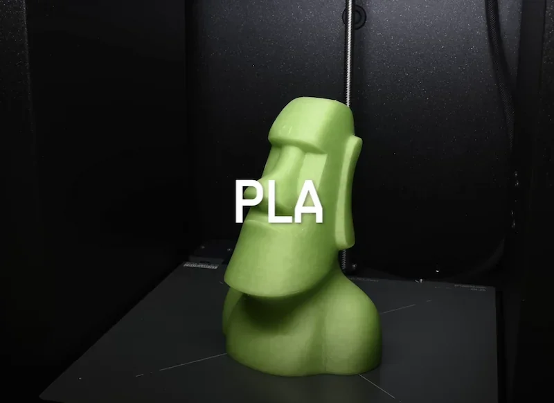 Green PLA Moai statue printed by Prusa Core One 3D printer, set against a dark background.