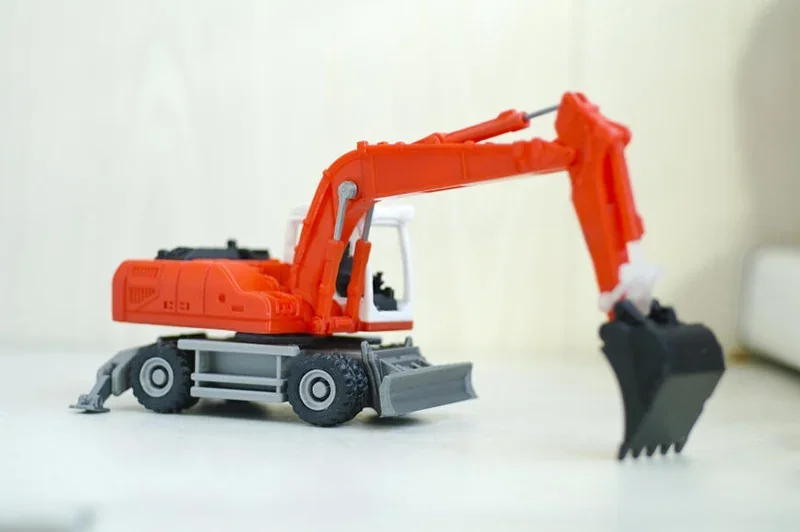 Red and gray toy excavator 3D printed by Prusa Mini on a white surface, showcasing detailed parts and design accuracy.