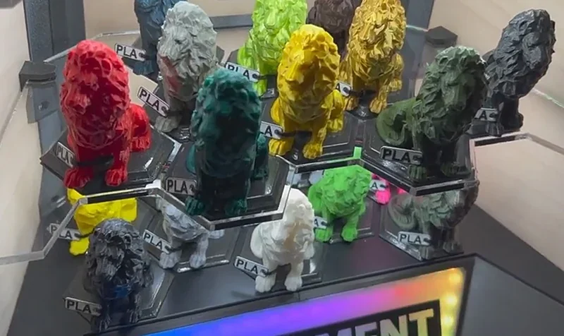 Colorful lion figurines 3D-printed by Prusa Mini displayed on a shelf, showcasing various PLA materials in a compact, organized arrangement.