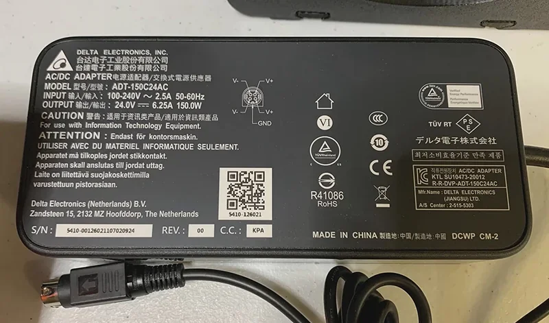Power adapter for Prusa Mini 3D printer, Delta Electronics model ADT-150C24AC, showing specifications and compliance symbols on a black casing.