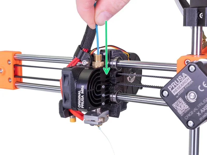 Prusa Mini 3D printer with components highlighted, featuring extruder assembly, branded parts, and axes.