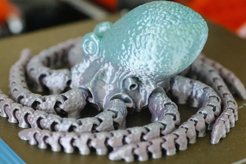 3D printed octopus model created by Prusa Mini, featuring detailed limbs and textured surface on a printer bed.