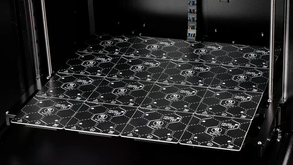 Prusa XL 3D printer bed with grid pattern and branding, showing multiple hexagonal sections ready for printing.