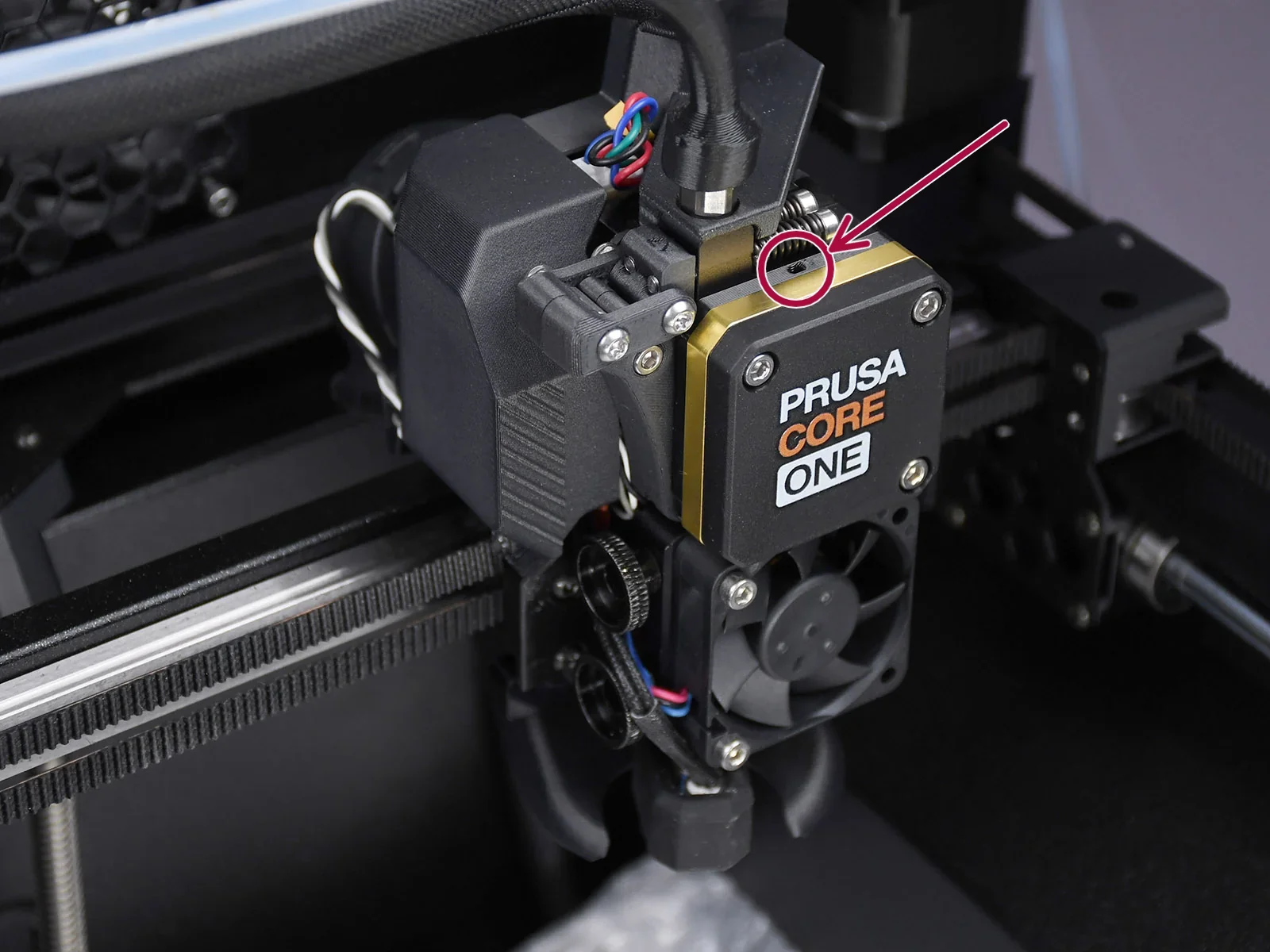 Prusa XL 3D printer extruder labeled "PRUSA CORE ONE" with integrated cooling fan and cables, highlighting high-precision engineering.