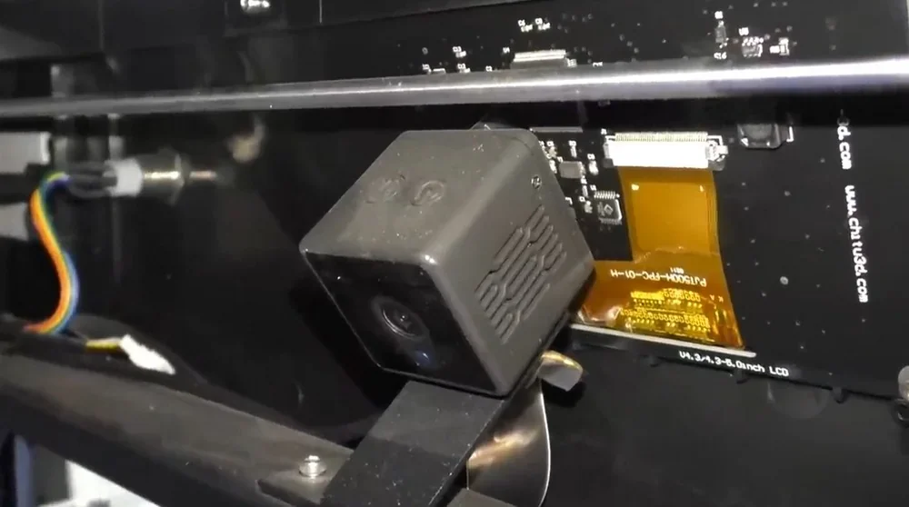Close-up view of Qidi i-Fast 3D printer's interior components and wiring, featuring a gray cube camera and circuit board connections.