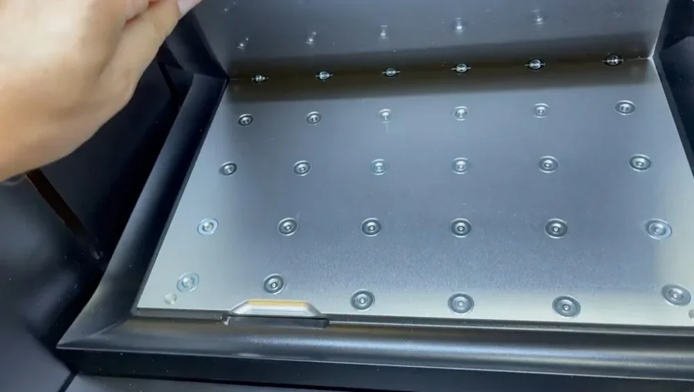 Qidi I-Fast 3D printer's metal build plate with grid layout for sample creation, viewed inside machine.