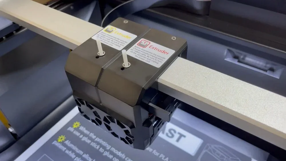 Qidi i-Fast 3D printer dual extruder detail, showing labeled extruder heads within a sleek frame, highlighting advanced printing capability.