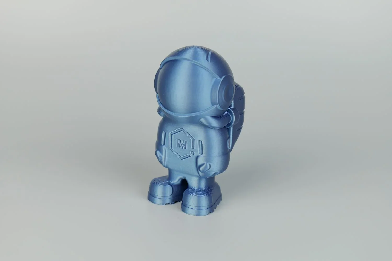 Blue 3D-printed astronaut figurine created by Qidi X Max on a plain background, showcasing detailed design elements and smooth finish.