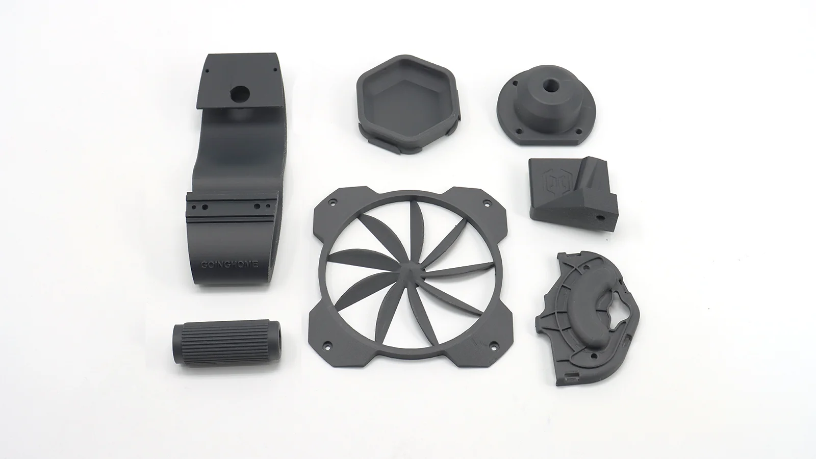 Various black 3D-printed parts created by Qidi X Max, featuring complex geometric shapes arranged on a white surface.