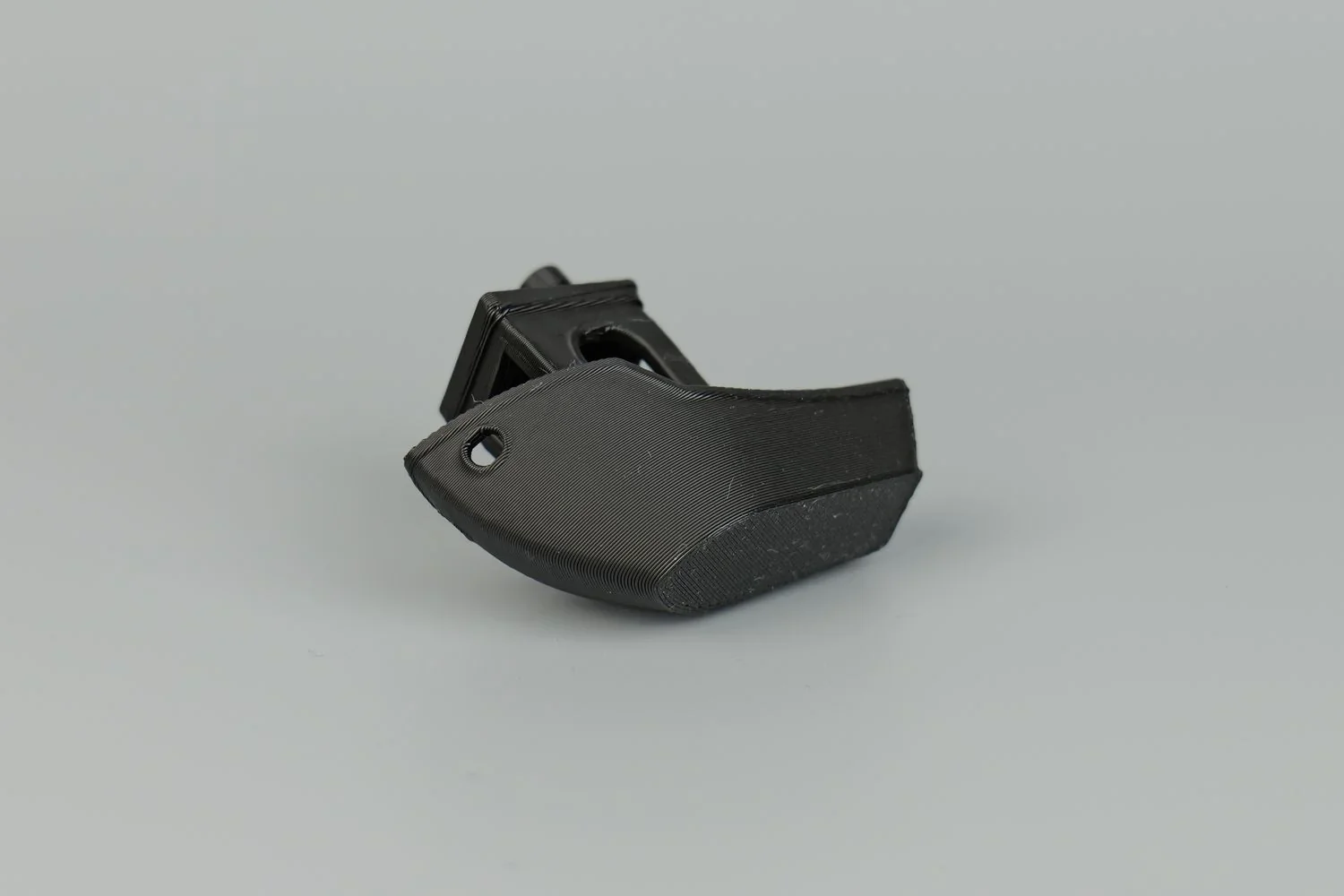 Black 3D printed part with smooth texture, created by QIDI X-Max, showcasing a sleek design and precise detailing on a plain background.