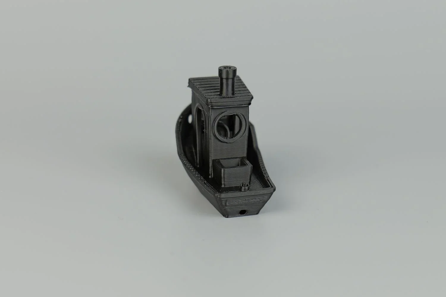 Black 3D-printed boat model on gray background, created by Qidi X Max.